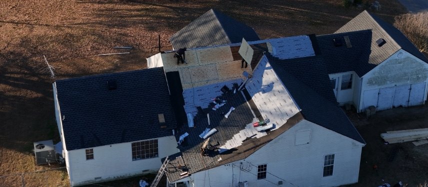 Aerial view of the crew tearing off the old roof and laying new decking and underlayment